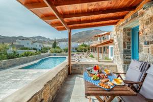 a table with food on it next to a swimming pool at Galazio Suites, Serifos in Livadakia