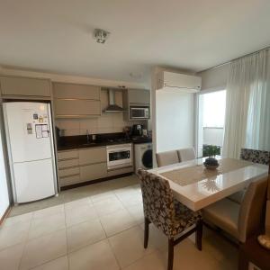 uma cozinha com uma mesa e um frigorífico branco em O seu apê na praia, 2 dormitórios, com piscina em Barra Velha