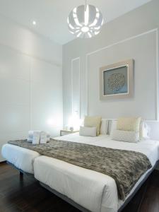 ein weißes Schlafzimmer mit einem großen Bett und einem Kronleuchter in der Unterkunft APARTAMENTO EN SANTA ANA - SOL (2H + 2B) in Madrid