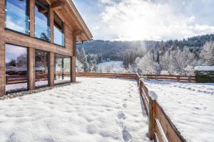 a house covered in snow with a fence at Chalet Aus Holz in Garmisch-Partenkirchen
