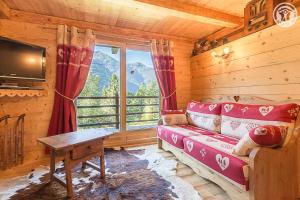 sala de estar con sofá, mesa y ventana en Chalet de Marie proche des Saisies en Queige