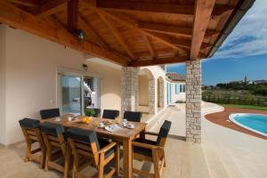 a dining room with a table and chairs and a swimming pool at Villa Aurora near Rovinj for 8 persons with sea view & whirlpool in Bale