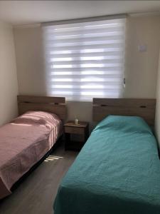 1 dormitorio con 2 camas y ventana grande en Departamento cercano a la playa en La Serena