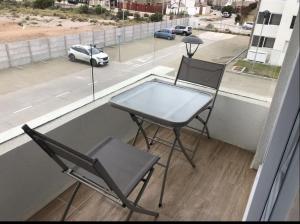 2 sillas y una mesa en un balcón con vistas a la calle en Departamento cercano a la playa en La Serena