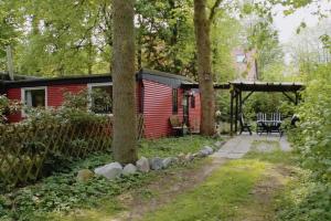 een rode hut in het bos met een patio bij Piraten Nest in Schortens