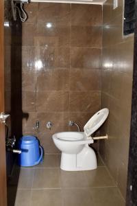 een badkamer met een toilet en een blauwe emmer bij Hotel Bharosa inn Naroda in Ahmedabad