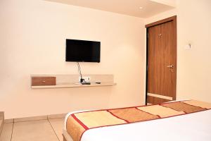 um quarto de hotel com uma cama e uma televisão na parede em Hotel Bharosa inn Naroda em Ahmedabad