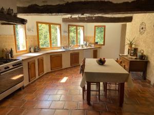 a kitchen with a table and a kitchen with a table and a tableablish at Gîte le Moulin Samsara in Homps