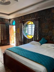 a bedroom with a large bed with a stone wall at Vaga Copper Castle in Vagamon