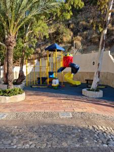 un parque infantil con tobogán en un parque con palmeras en Sunsea Village 3d, en Calpe
