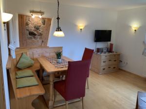 comedor con mesa, sillas y TV en Ferienwohnung Lindenhof en Lenzkirch