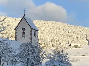 una iglesia con una torre de reloj en la nieve en Ferienwohnung Lindenhof en Lenzkirch