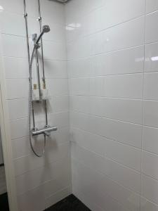 a shower in a bathroom with white tiles at Yksiö keskustassa saunalla in Iisalmi