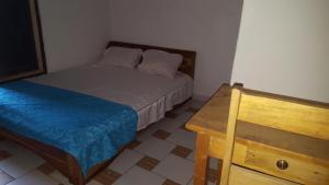 a small bedroom with a bed and a wooden table at 2 chambres salon Baguida in Lomé