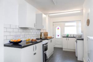 a white kitchen with black counter tops and a window at Bright House in Hartlepool