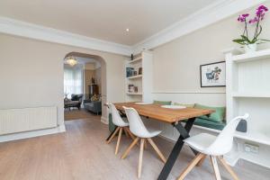 uma sala de jantar com uma mesa de madeira e cadeiras brancas em Oakwood House em Dublin