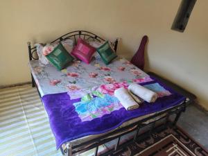 Cama con manta y almohadas moradas en Hostel Magic Home Stay jaisalmer en Jaisalmer
