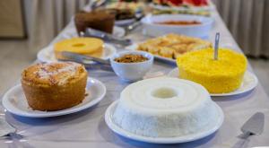 uma mesa com diferentes tipos de bolos e pastelarias em Pousada Veneza em Itabuna