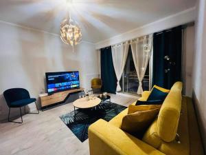 a living room with a yellow couch and a tv at AVENUE DE CHAMPAGNE in Épernay