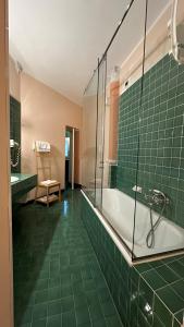 Hotel Roma في بولونيا: حمام ذو بلاط أخضر مع حوض استحمام وكرسي