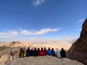 a group of people sitting on a rock in the desert at Desert Gate Camp in Wadi Rum