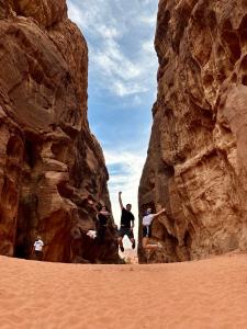 a group of people jumping off of rocks in the desert at Desert Gate Camp in Wadi Rum