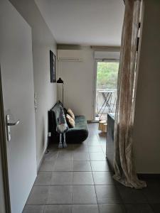 sala de estar con sofá y ventana en Appartement cosy climatisé dans résidence fermée, en Sarrola-Carcopino