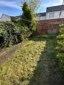 a grassy yard with a building and a fence at Modern 3BD Home Doncaster South Yorkshire in Doncaster