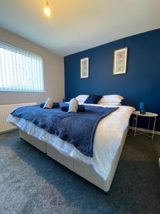 a bedroom with a large bed with a blue wall at Modern Home with Free Parking Sleeps 6 in Leeds