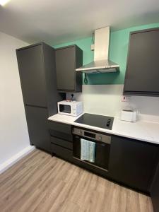 a kitchen with a stove and a microwave at Modern Home with Free Parking Sleeps 6 in Leeds