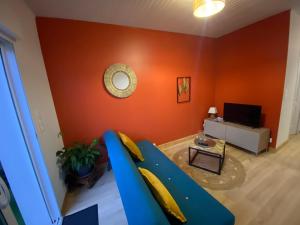 a living room with a blue couch and an orange wall at Le cosy in Labarde