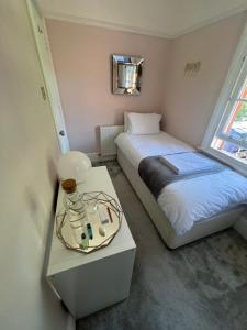 a bedroom with two beds and a table with a mirror at The Victorian Rooms in Surbiton