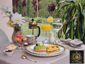 a table with a plate of food and glasses of orange juice at Hotel Mansion Sant Serrant Medellín- Aeropuerto Rionegro in Marinilla