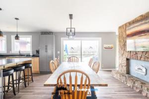 a kitchen with a dining table and a fireplace at Stunning All Season Waterfront Cottage By Grace's Landing Short Term Rental and & Long Term Accommodation Corbyville Ontario in Belleville