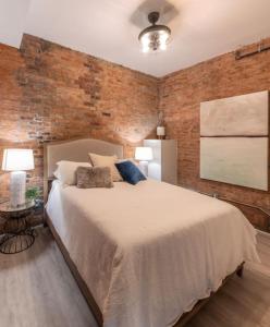 a bedroom with a large bed and a brick wall at Parlor - Explore OTR and DT from Restored 1894 Italianate in Cincinnati