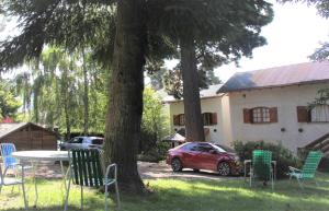 een rode auto geparkeerd naast een tafel en stoelen bij LA PONDEROSA Apart Hotel in Bariloche