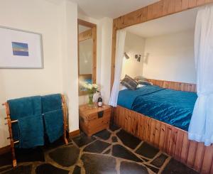 a bedroom with a wooden bed with a blue blanket at Tigh Mairi at Mary's Thatched Cottages in Elgol
