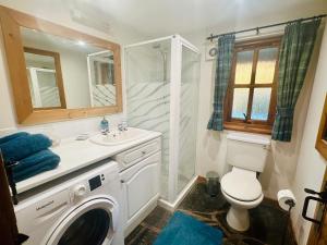 a bathroom with a washing machine and a sink at Tigh Mairi at Mary's Thatched Cottages in Elgol