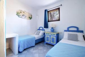 two beds in a room with blue and white at Residence I Cormorani Bis in Baja Sardinia