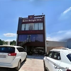 two cars parked in a parking lot in front of a building at Hotel delight deluxe in Pipra Dewās