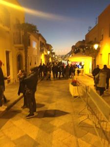 Un groupe de personnes marchant dans une rue la nuit dans l'établissement Casa vacanze Poma, à Custonaci