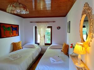 two beds in a room with a mirror and a window at Cosy lake house, μια ανάσα πριν τη λίμνη in Kalyvia