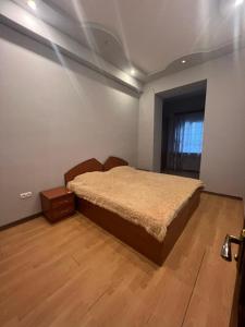 1 dormitorio con 1 cama y suelo de madera en Byuzand 7 en Ereván