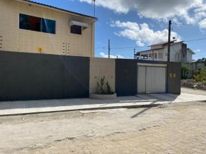 a fence next to a building with a garage at Aconchego MCC in João Pessoa