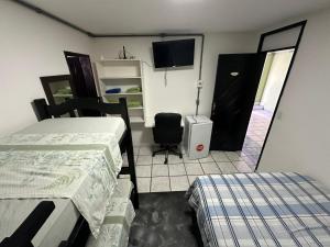 a room with two beds and a tv and a door at Dunas Hostel in Natal