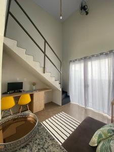 a living room with a staircase and two yellow chairs at Lofts Umuarama Residence in Uberlândia