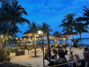 un grupo de personas sentadas en la playa por la noche en Sand Resort @ Country Garden Danga Bay, en Johor Bahru