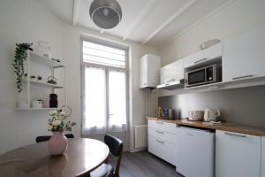 AppartUnique - Chez Murillo في فيشي: مطبخ به دواليب بيضاء وطاولة عليها مزهرية
