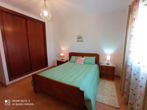a bedroom with a bed with a green comforter at Beach House Haller in Aljezur