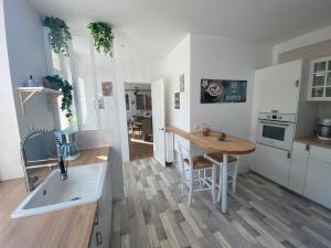 a kitchen with a sink and a table in it at Le cottage des Vaux in Senlisse